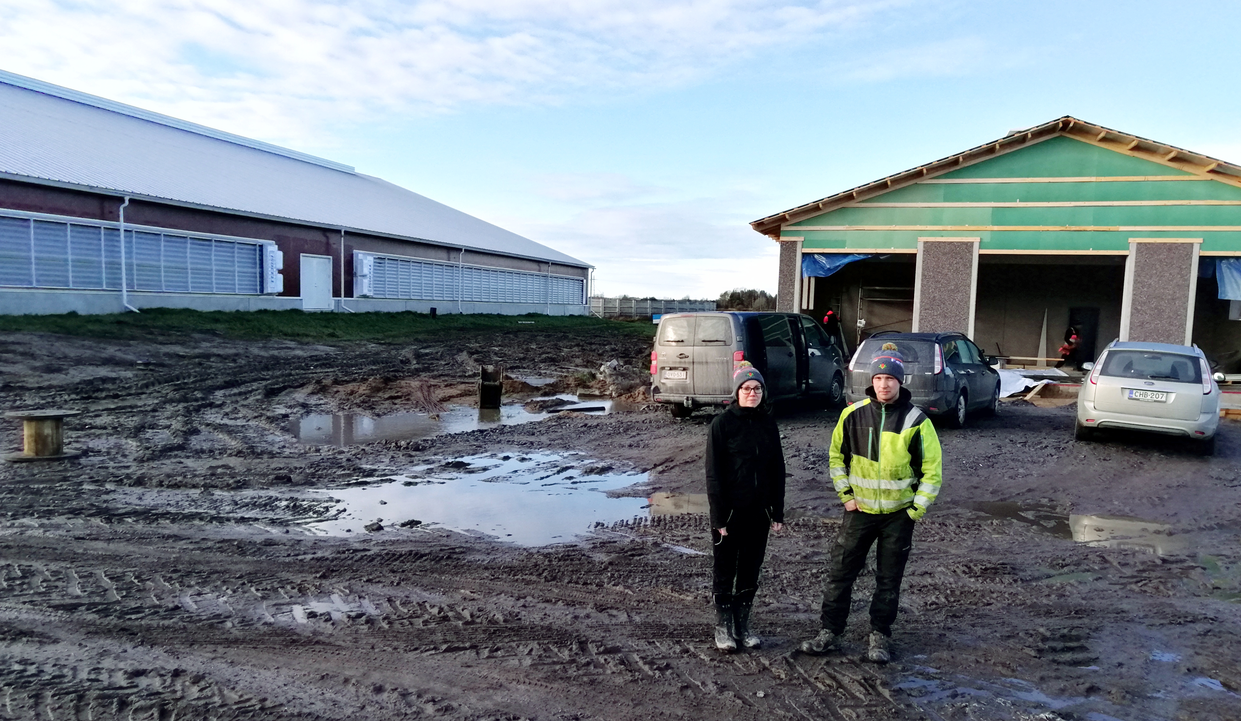 Efter höststormen skiner novembersolen igen! Tarja och Ari Peltokangas vid det nybyggda kalvstallet. Bakom syns ladugården.